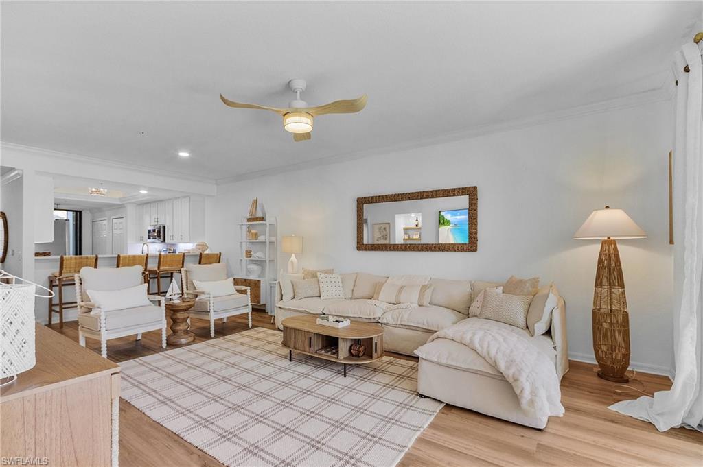 Living room with hardwood / wood-style floors, ceiling fan, and ornamental molding