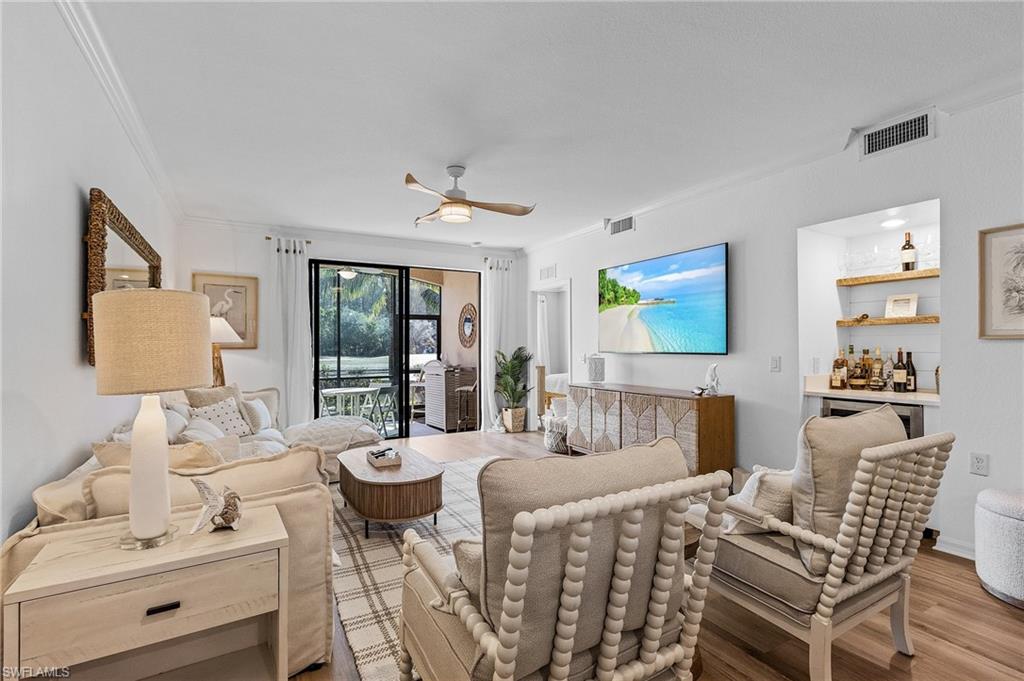 Living room featuring light hardwood / wood-style flooring, ceiling fan, and bar area.