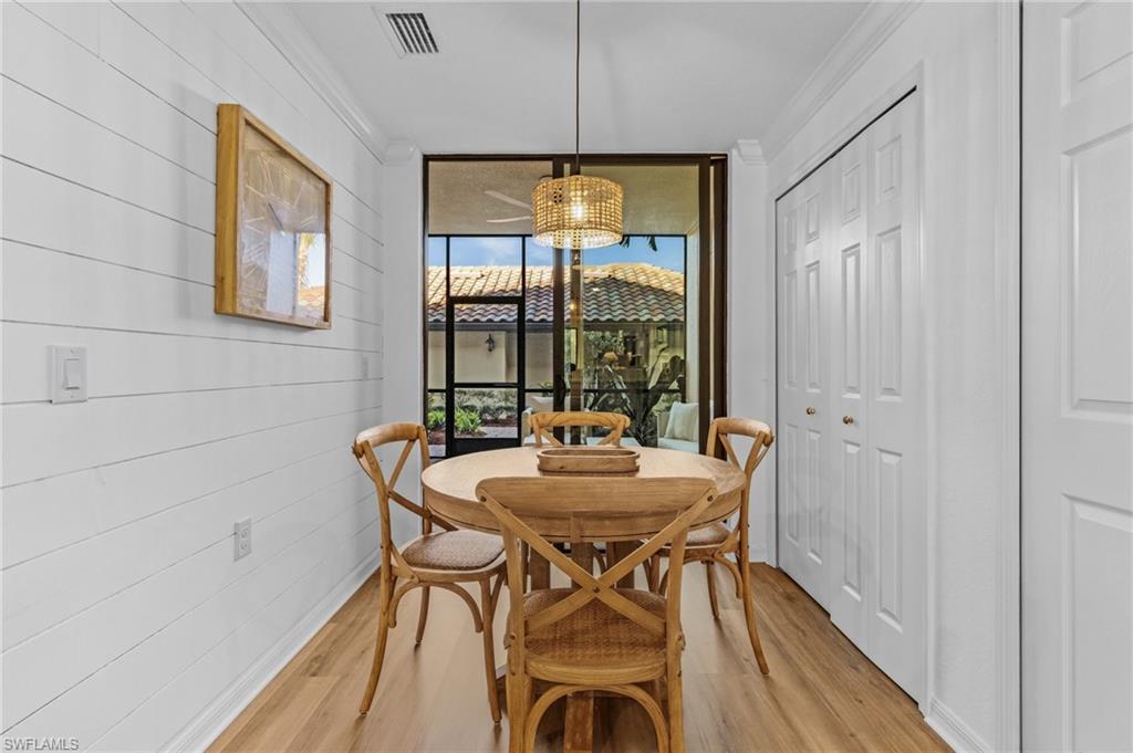 Dining space with wood walls, light hardwood / wood-style floors, and ornamental molding