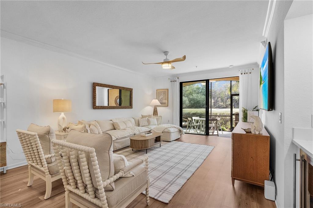 Living room with ceiling fan, ornamental molding, and hardwood / wood-style flooring.