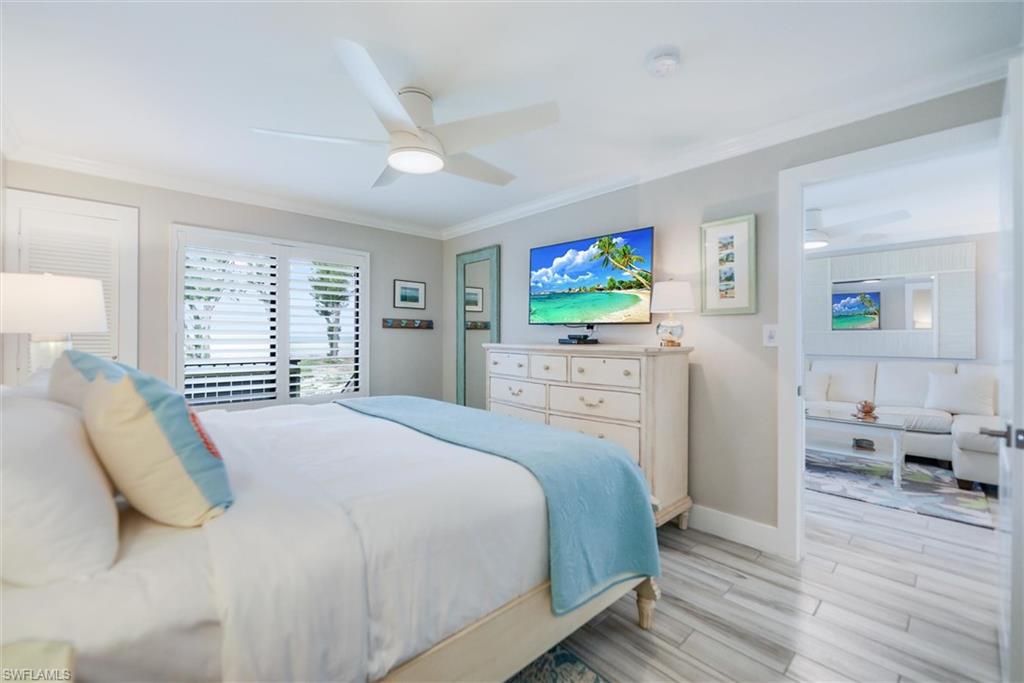 Bedroom with wood tiled floors, ornamental molding, and a ceiling fan