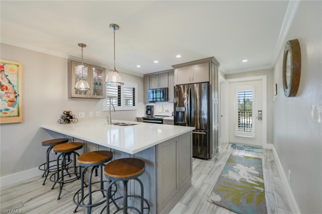 Kitchen featuring a breakfast bar, stainless steel appliances, a peninsula, wood tiled floors, and gray cabinets
