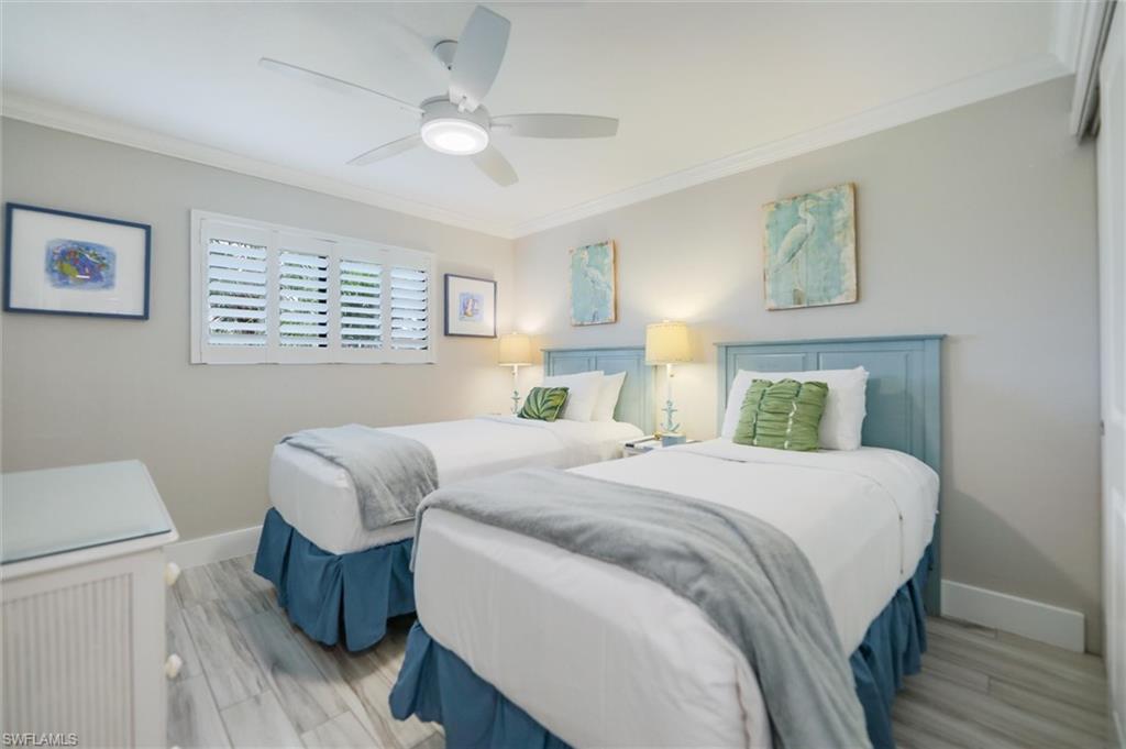Bedroom featuring crown molding, wood finished floors, and a ceiling fan