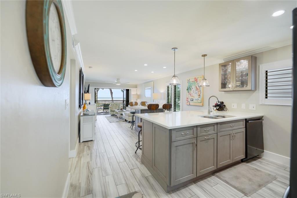 Kitchen featuring open floor plan, a breakfast bar area, glass insert cabinets, pendant lighting, and a peninsula