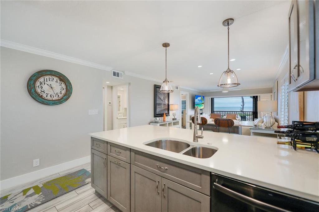 Kitchen with open floor plan, dishwasher, hanging light fixtures, crown molding, and wood tiled floors