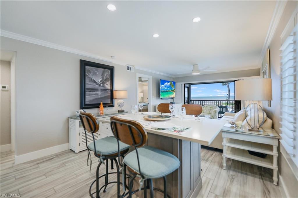 Kitchen featuring ornamental molding, light countertops, recessed lighting, light wood-style floors, and a breakfast bar