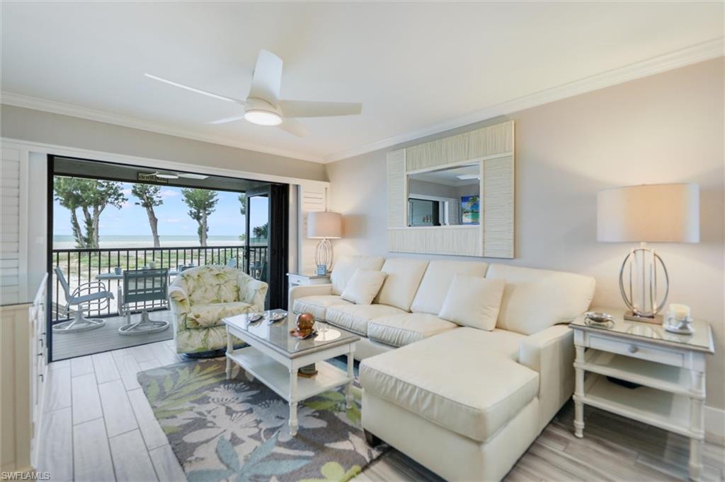 Living room with wood finish floors, crown molding, a water view, and ceiling fan