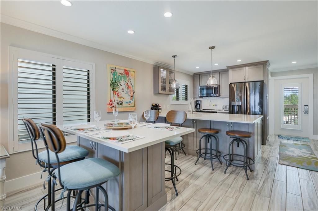 Kitchen with a breakfast bar, crown molding, gray cabinets, recessed lighting, and appliances with stainless steel finishes