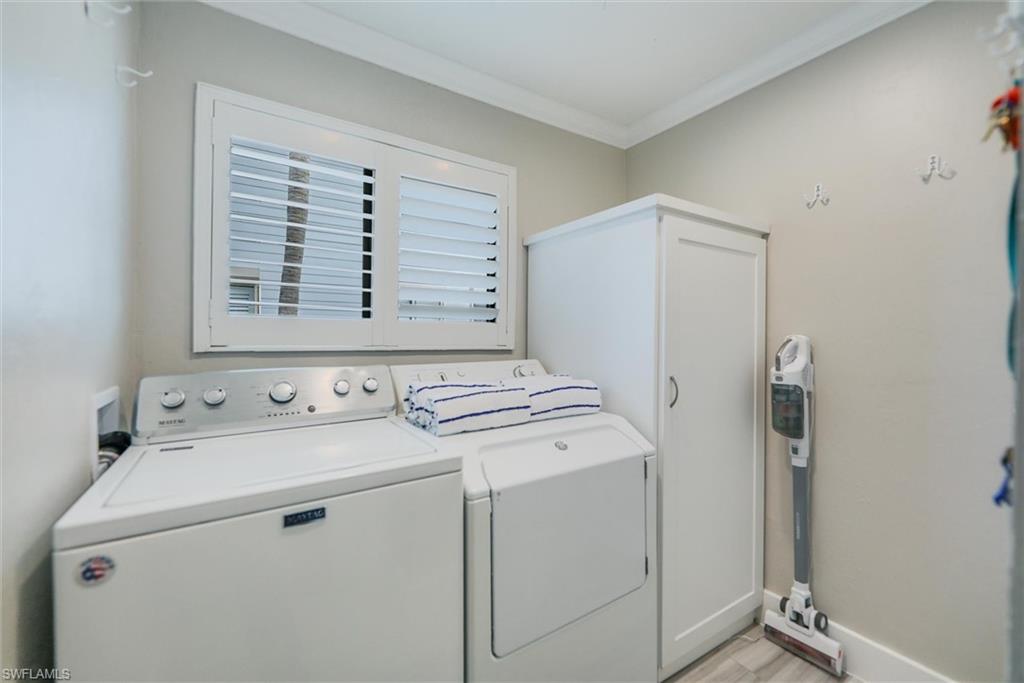 Washroom with washer and clothes dryer, crown molding, and light wood-style flooring