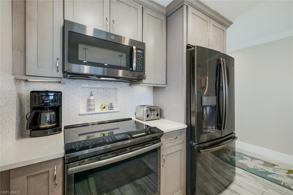 Kitchen featuring stainless steel appliances, gray cabinets, tasteful backsplash, and light wood-style floors