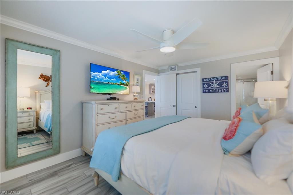 Bedroom with ornamental molding, ensuite bathroom, wood finished floors, ceiling fan, and a closet
