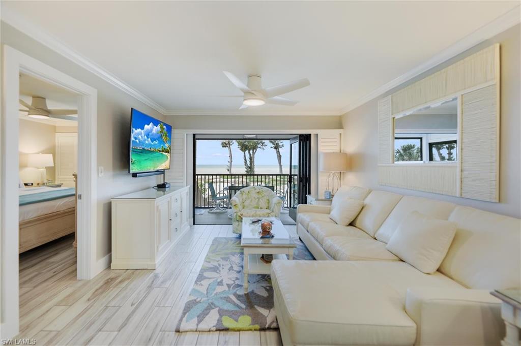Living area featuring a ceiling fan, crown molding, and wood finish floors