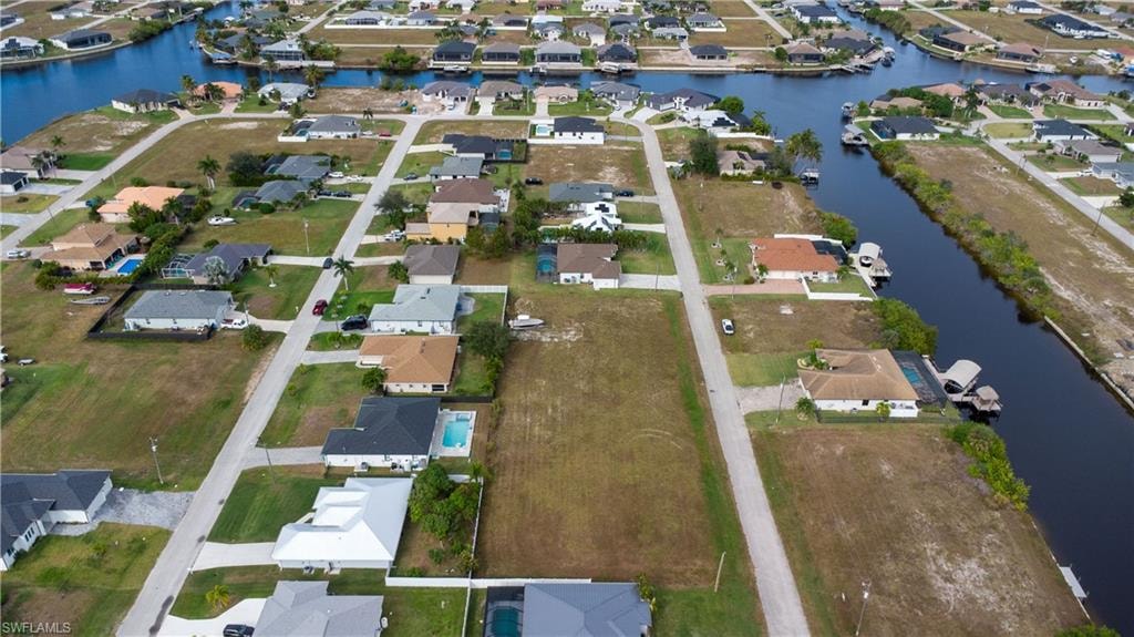 Aerial view of property and surrounding area featuring nearby suburban area and a large body of water