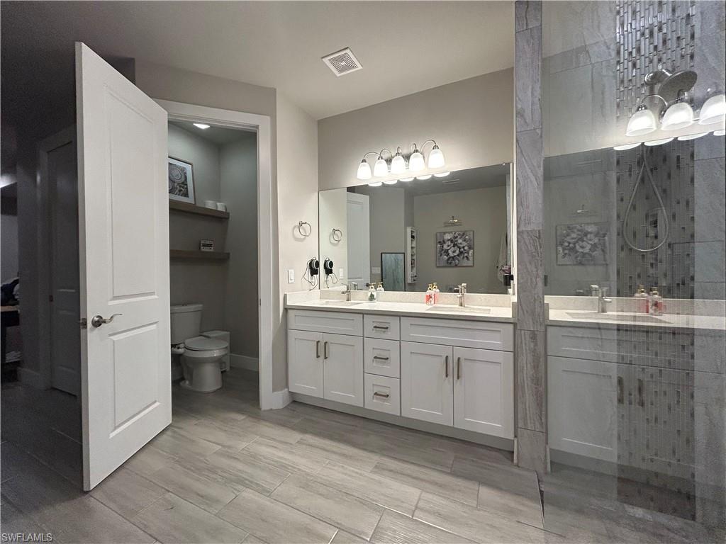 Bathroom with double vanity, a stall shower, and wood look finish floors
