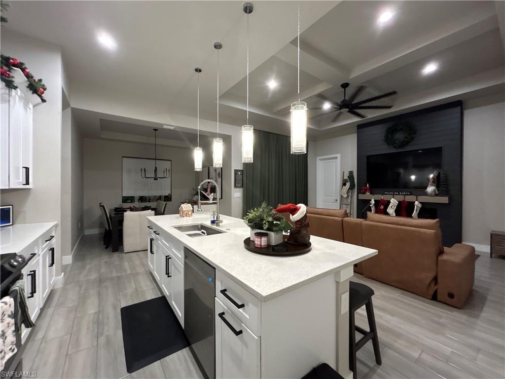 Kitchen featuring open floor plan, white cabinetry, light stone countertops, coffered ceiling, and a kitchen breakfast bar