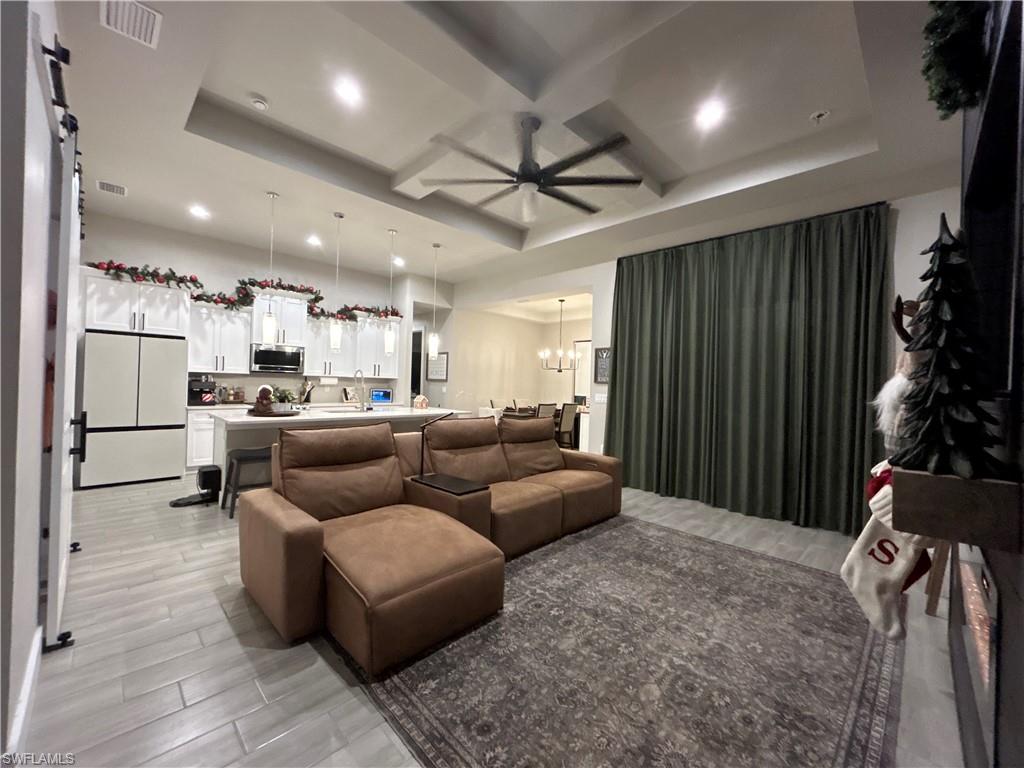 Livingroom with a tray ceiling, ceiling fan, coffered ceiling, and recessed lighting