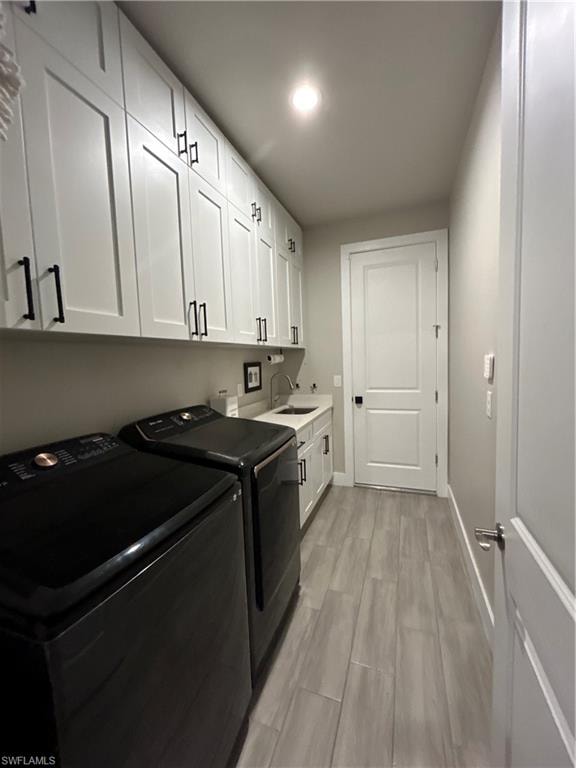 Washroom with light wood-style flooring, washer and dryer, cabinet space, and recessed lighting
