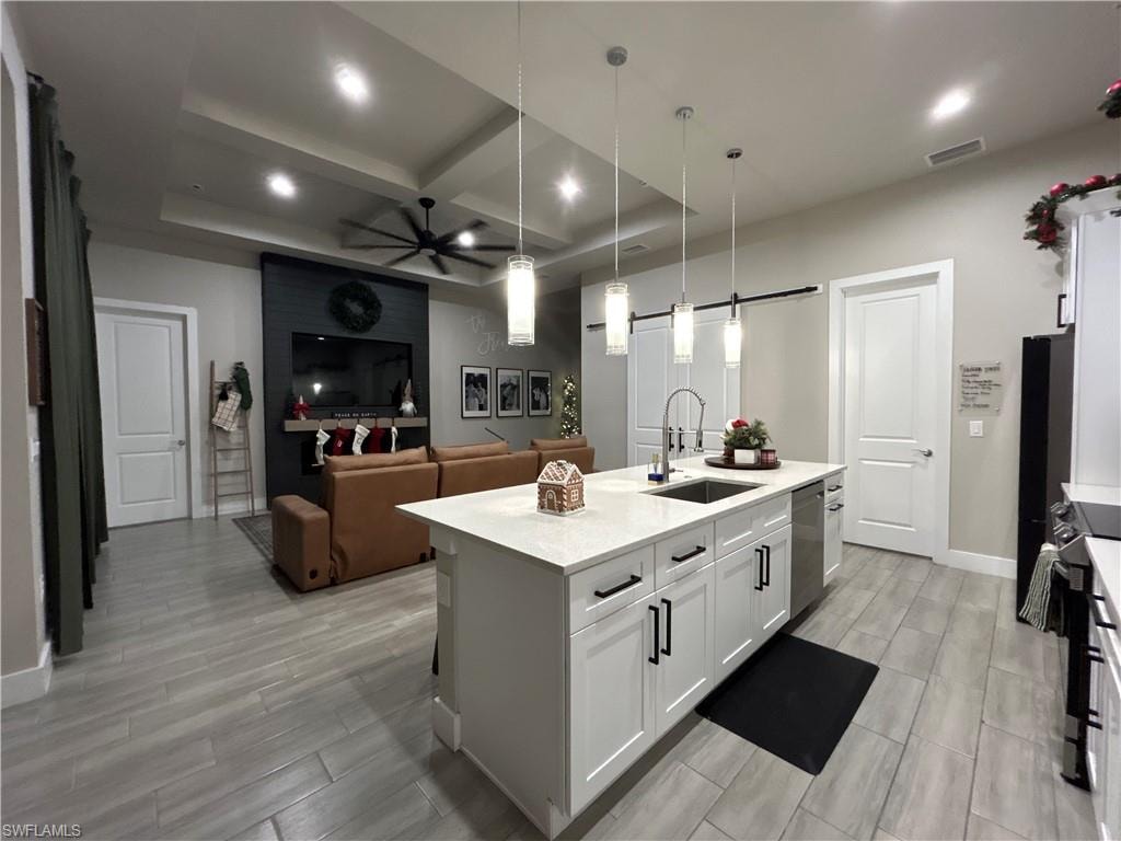 Kitchen with white cabinets, coffered ceiling, ceiling fan, decorative light fixtures, and wood look floors