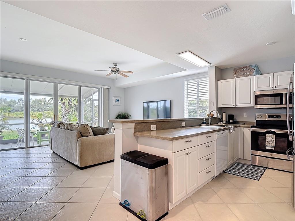 Kitchen featuring a peninsula, appliances with stainless steel finishes, white cabinetry, open floor plan, and light tile patterned floors