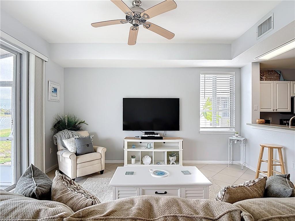 Living room featuring a ceiling fan, light tile patterned floors, and plenty of natural light