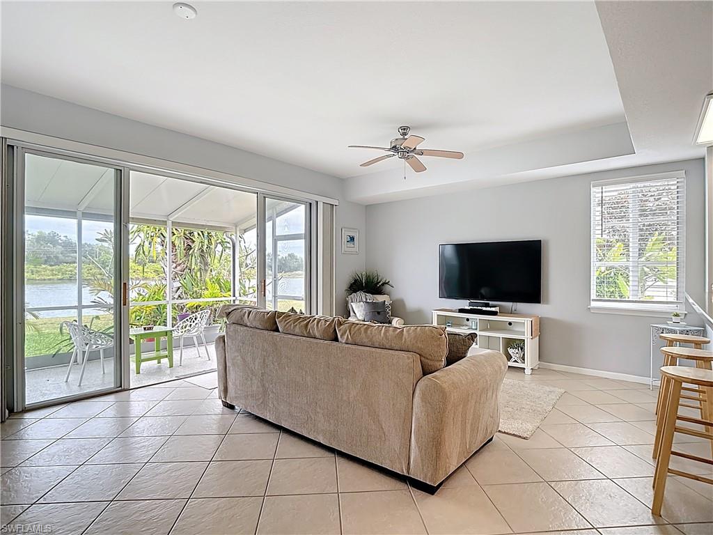Living area with a water view, a ceiling fan, and light tile patterned flooring