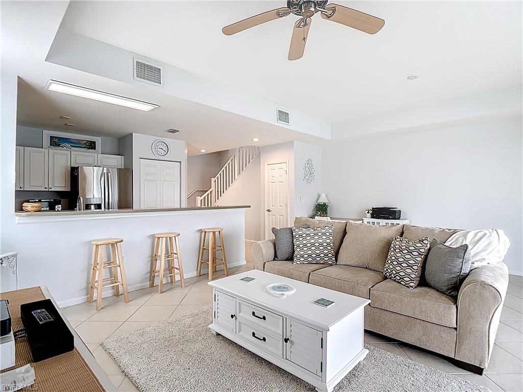 Living area with stairs, light tile patterned floors, a ceiling fan, and recessed lighting