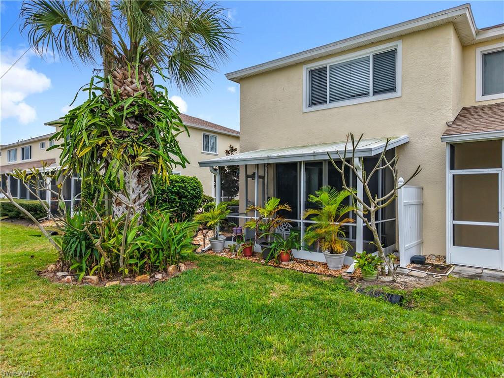 Back of property featuring a sunroom, stucco siding, and a yard