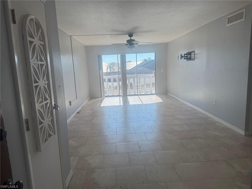 Empty room with a textured ceiling and ceiling fan
