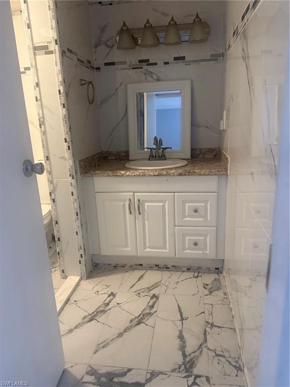 Bathroom featuring light marble finish floors and vanity