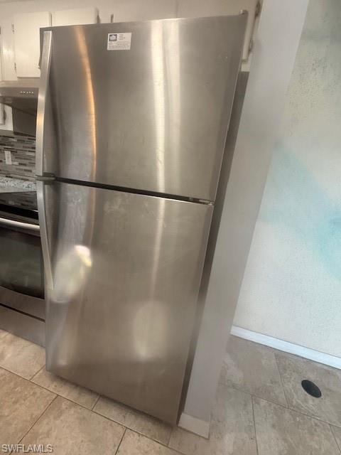 Kitchen view of appliances with stainless steel finishes, extractor fan, and a textured wall