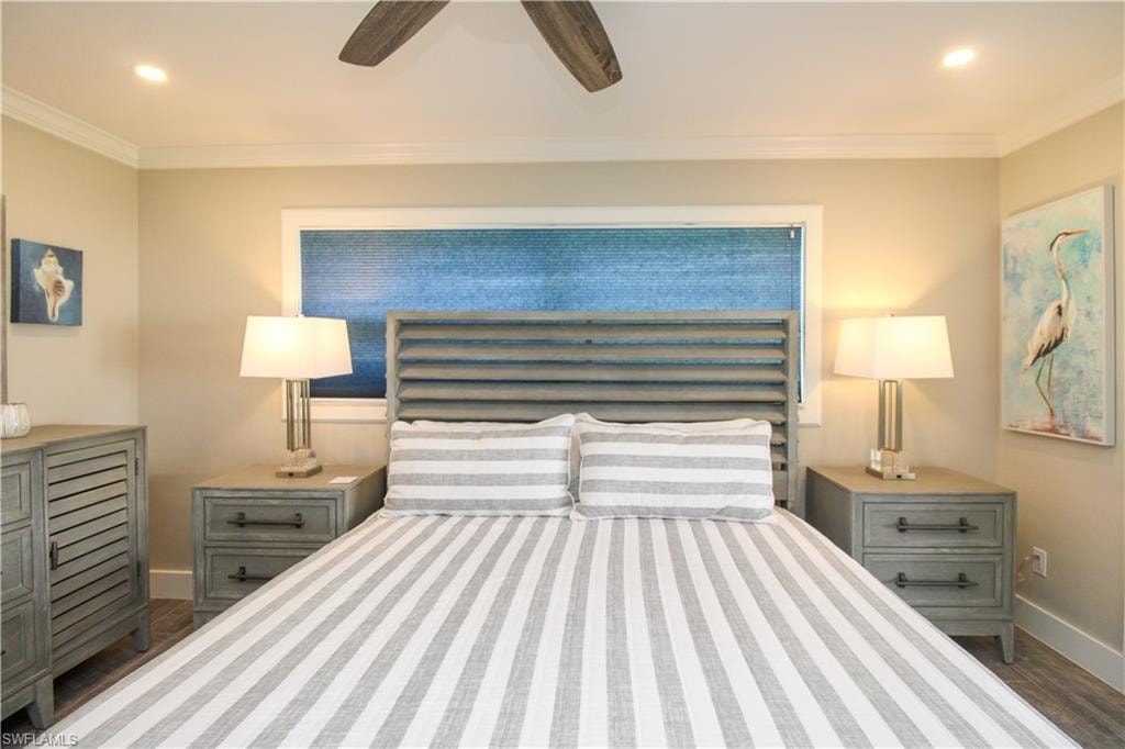 Bedroom with ceiling fan, crown molding, and dark wood-type flooring