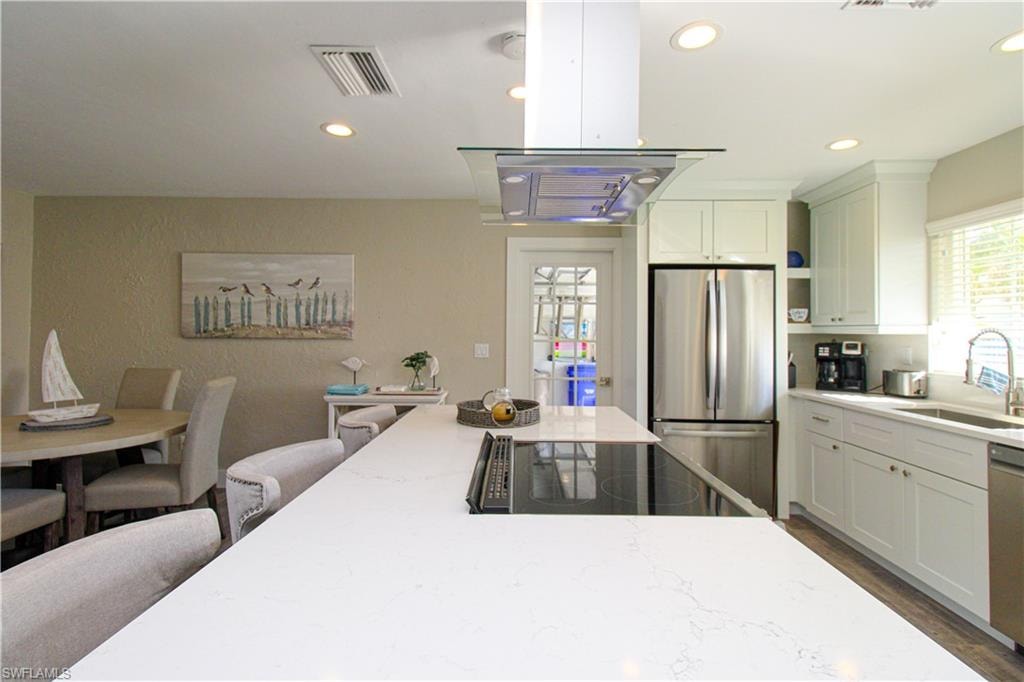 Kitchen with white cabinets, sink, dark hardwood / wood-style floors, appliances with stainless steel finishes, and light stone counters