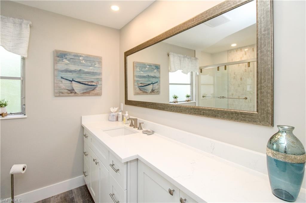 Bathroom with vanity, an enclosed shower, and wood-type flooring