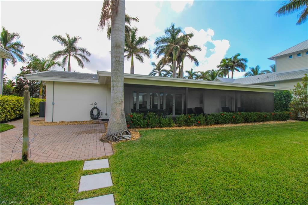 Back of property with a lawn and a sunroom