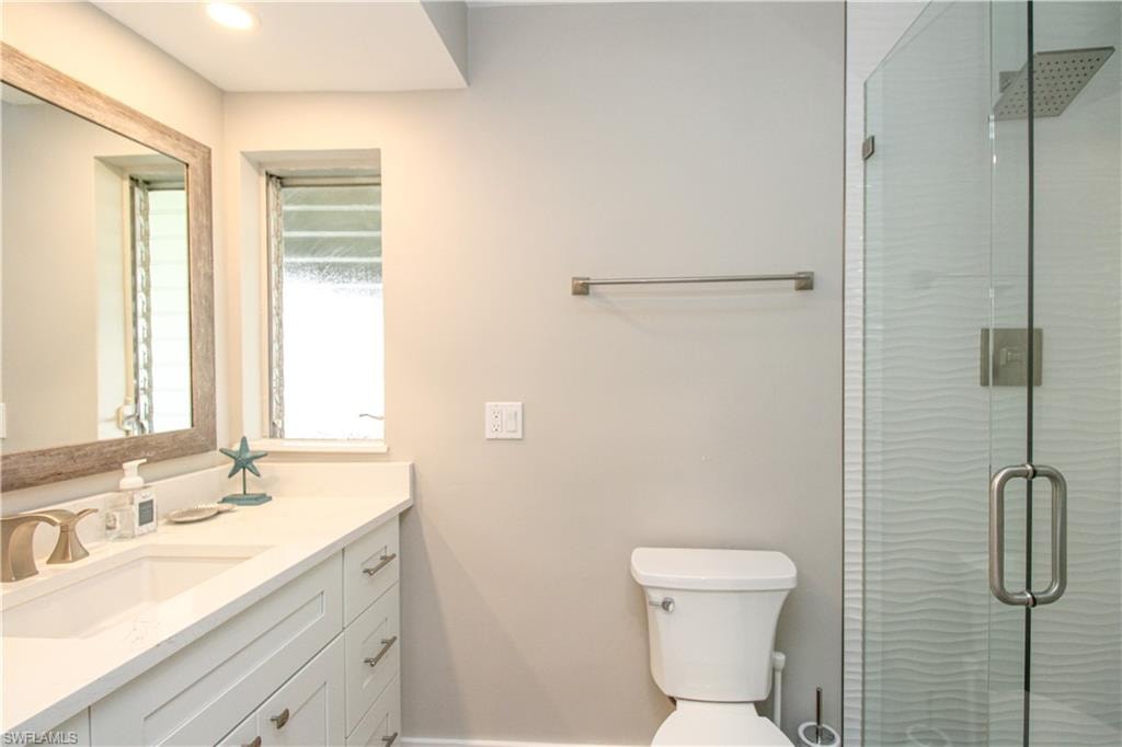 Bathroom with vanity, toilet, and an enclosed shower