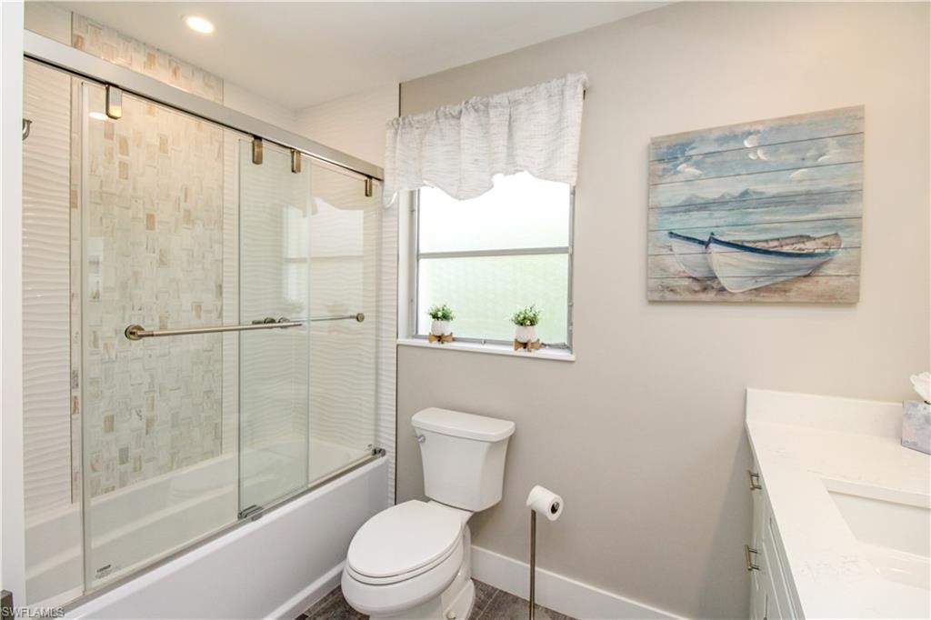 Full bathroom featuring vanity, toilet, and bath / shower combo with glass door