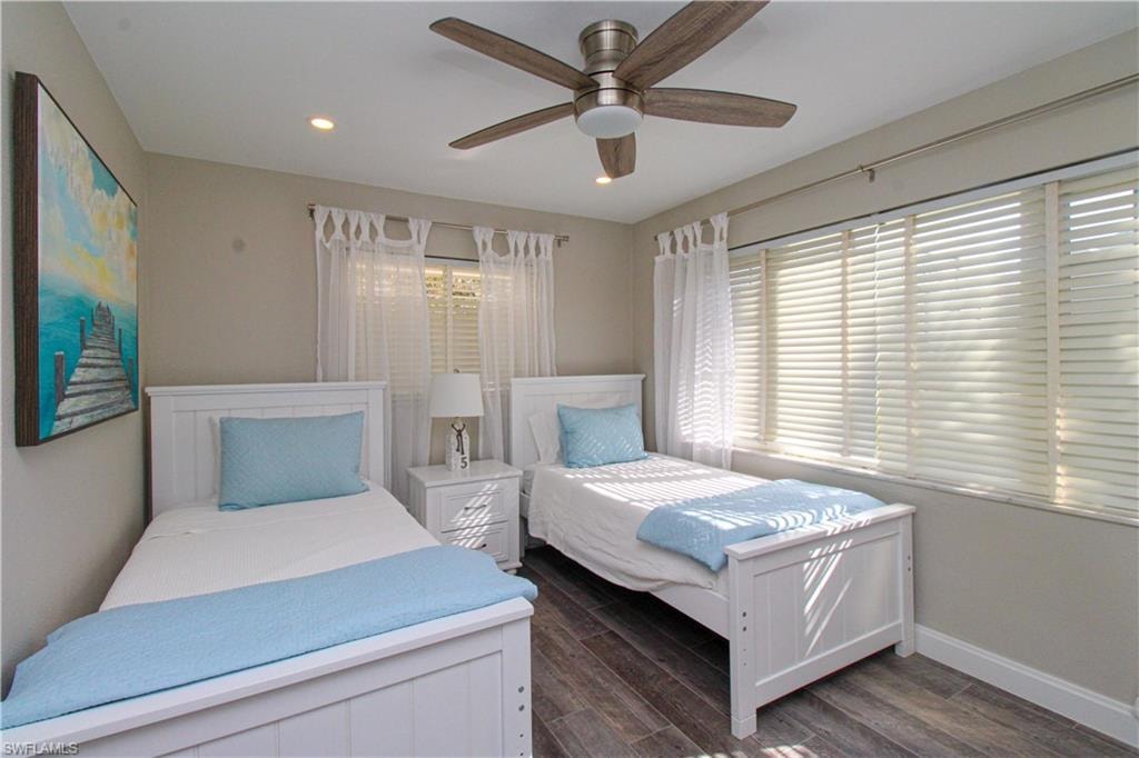 Bedroom featuring multiple windows, ceiling fan, and dark wood-type flooring