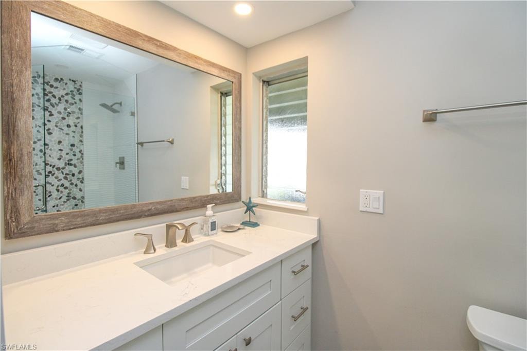 Bathroom with toilet, vanity, and walk in shower