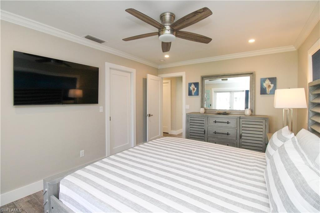 Bedroom with light hardwood / wood-style flooring, ceiling fan, and ornamental molding