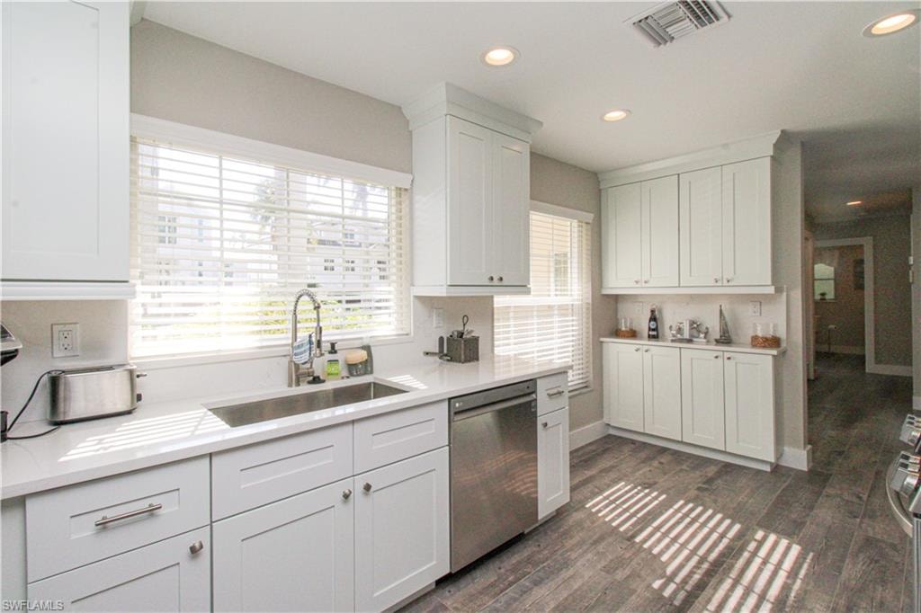 Kitchen with white cabinetry, stainless steel dishwasher, dark wood-type flooring, and sink