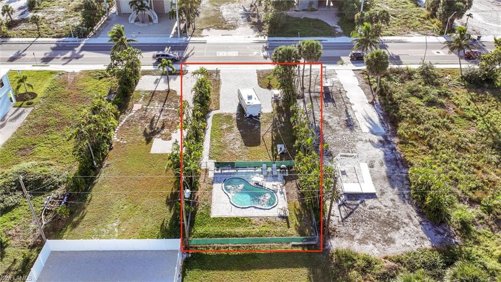 Aerial view of property and surrounding area featuring property parcel outlined and a pool area