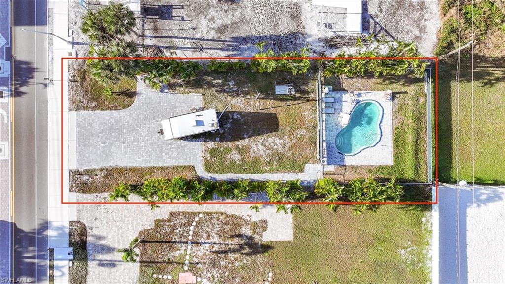 Aerial view of property and surrounding area with a pool and property boundaries highlighted