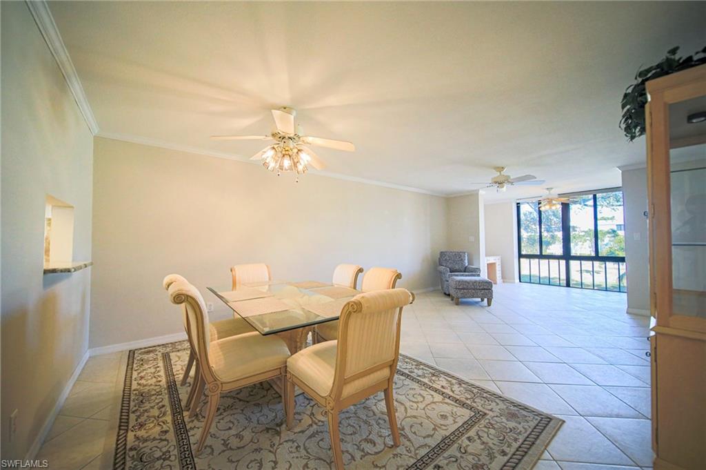 The Dining Area Featuring Crown Molding, Large Glass Table And 6 Chairs, Light Tile Patterned Flooring, And A Kitchen Passthrough!