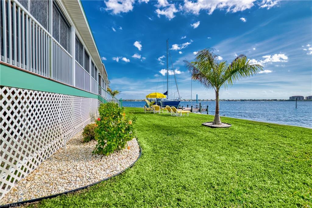 View of green lawn with a water view and a boat dock