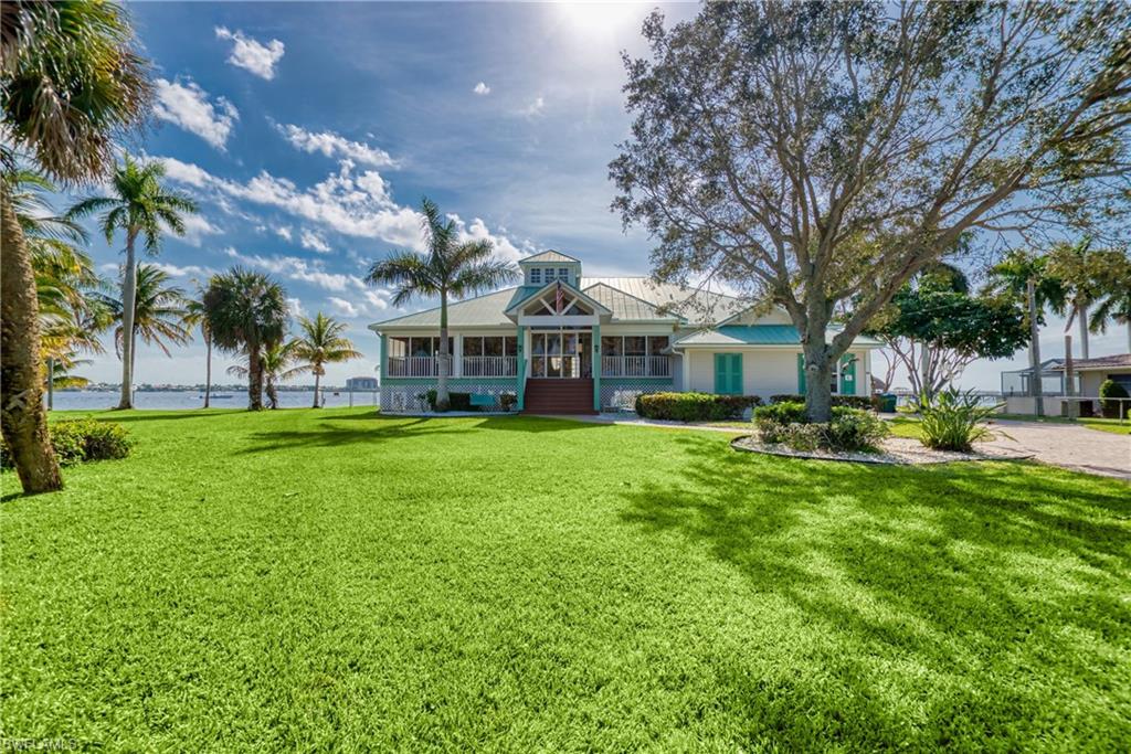 View of front of house featuring a porch, a front lawn, a water view, and a metal roof