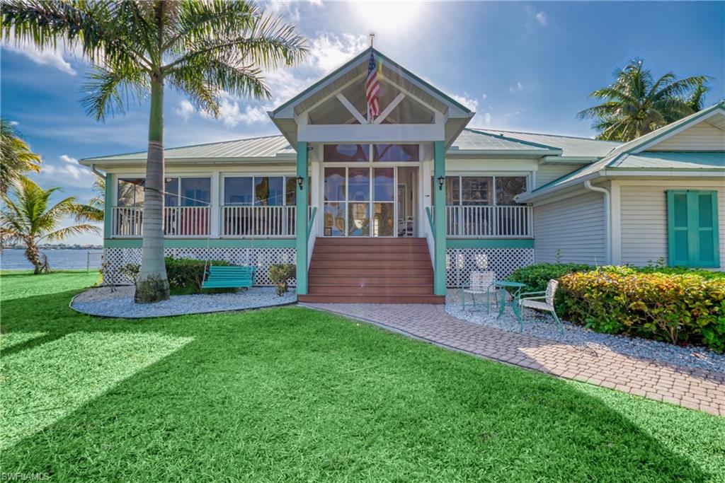 View of front of home featuring a front yard, a patio area, a sunroom, a wooden deck, and stairway