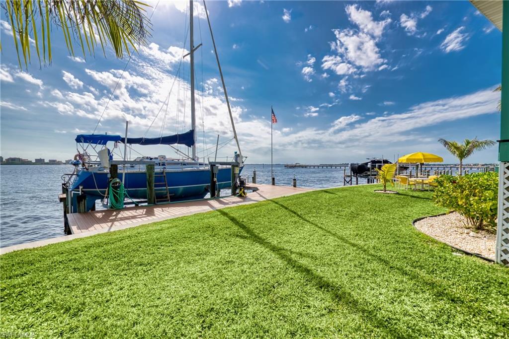 Dock area featuring a lawn, boat lift, and a water view