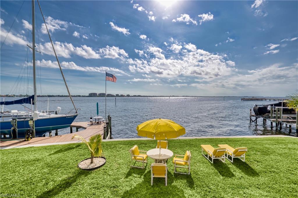 Dock area with boat lift, a lawn, and a water view