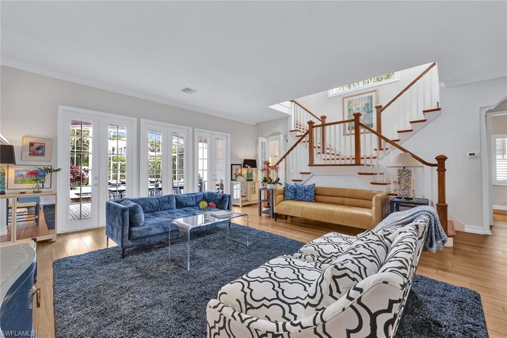 Living room with crown molding, french doors, and light wood-type flooring