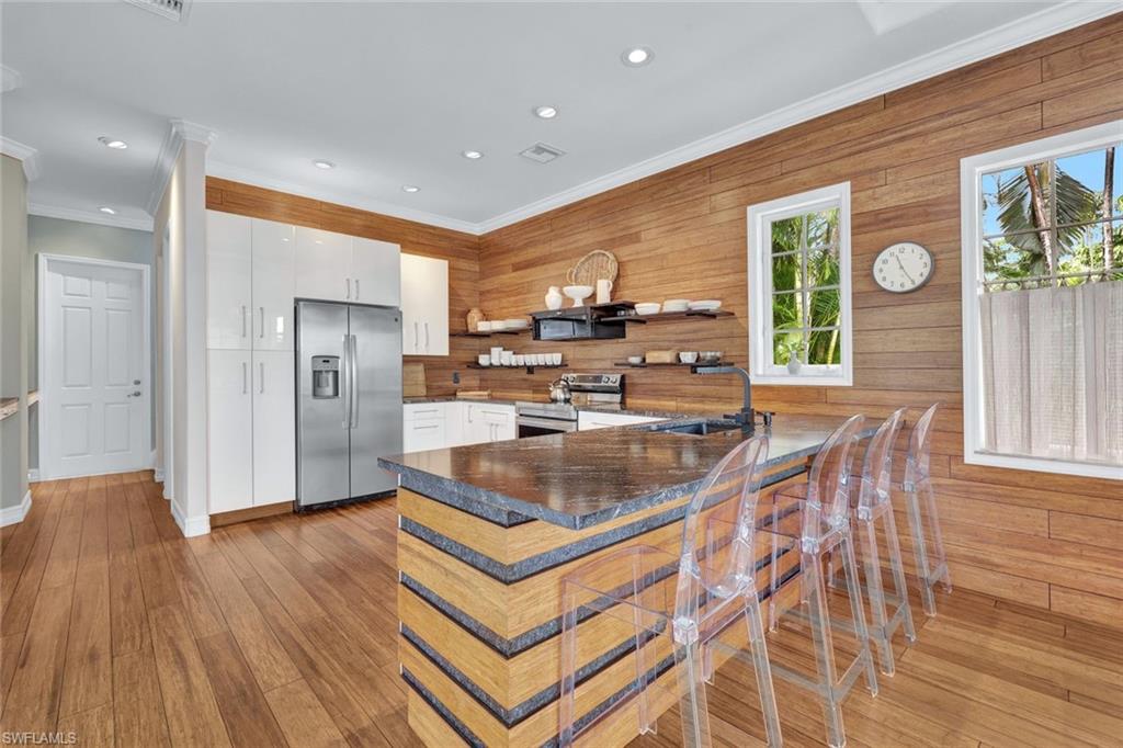 Kitchen with white cabinetry, kitchen peninsula, appliances with stainless steel finishes, ornamental molding, and sink